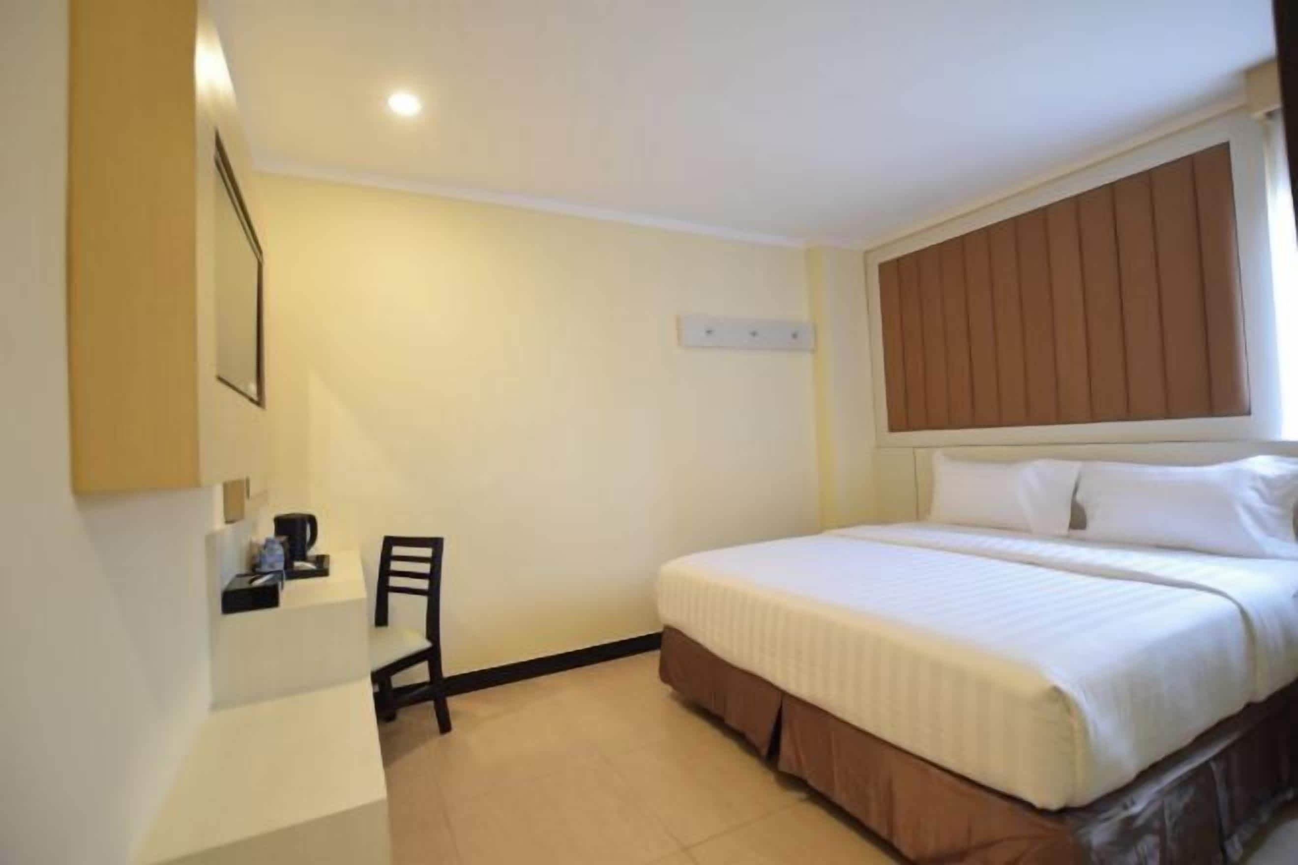 A hotel room with a bed, a desk, and a chair.