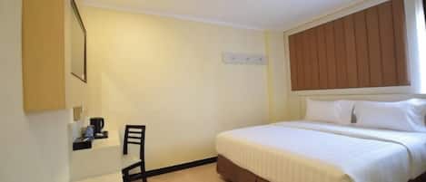 A hotel room with a bed, a desk, and a chair.