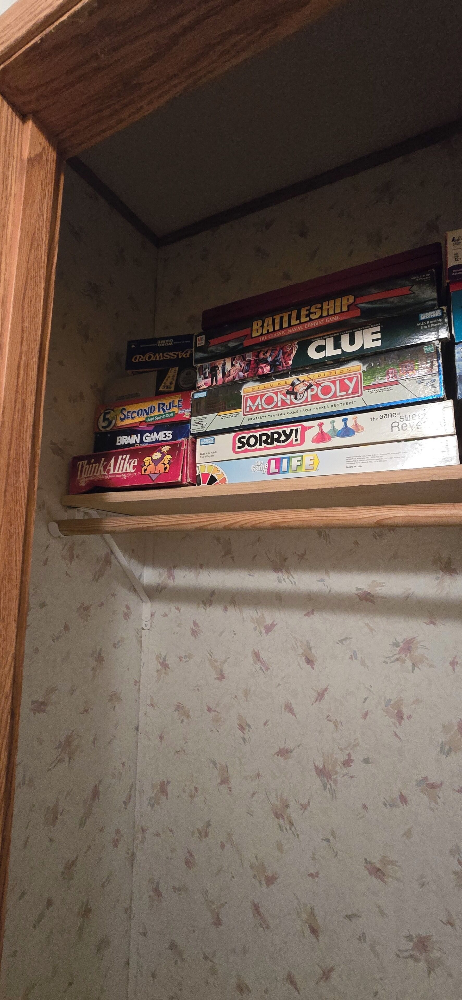 A shelf with various board games including Battleship, Clue, Monopoly, and others.