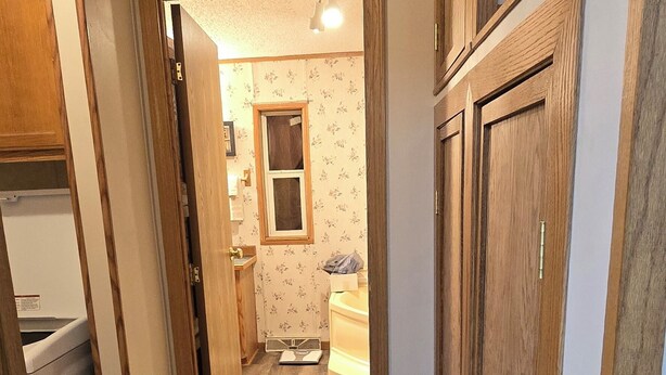 A narrow hallway with wooden flooring and doors leading to a bathroom with a window and a sink. - Trails and fishing paradise  (Nashwauk)