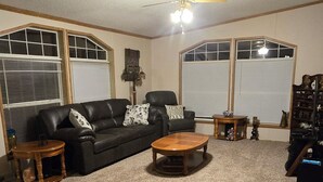 A living room with a black leather sofa, two wooden side tables, a coffee table, and a ceiling fan. - Trails and fishing paradise  (Nashwauk)