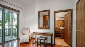 A room with a large sliding glass door, a wooden floor, a small table, a chair, and a mirror on the wall. - Orchid Pool Villa Lavish Villa in Perfect Location (Phuket)
