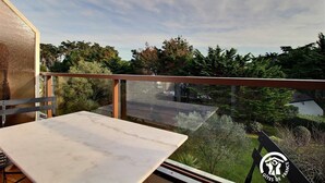 A balcony with a marble table, glass railing, and a view of trees and a bridge. - Marine calm - QUIBERON (QUIBERON)
