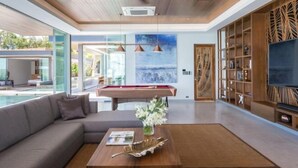 A modern living room with a pool table, a sofa, a coffee table, and a TV. - Exclusive Sea Renity A Beachfront Villa Retreat Sleeps 12 Adults and 6 Kids (Koh Samui)