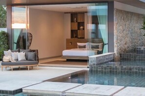 A modern bedroom with a glass door leading to a pool area, a sofa, and a bed with a nightstand. - Exclusive Sea Renity A Beachfront Villa Retreat Sleeps 12 Adults and 6 Kids (Koh Samui)