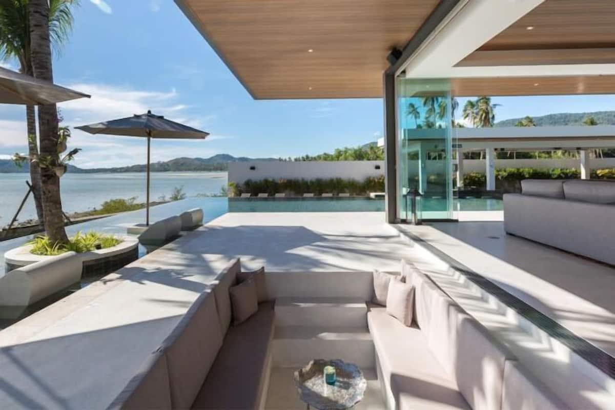 Ein moderner Außenbereich mit Sitzgelegenheit und Blick auf einen Pool, inklusive einer Couch und einem Glastisch.