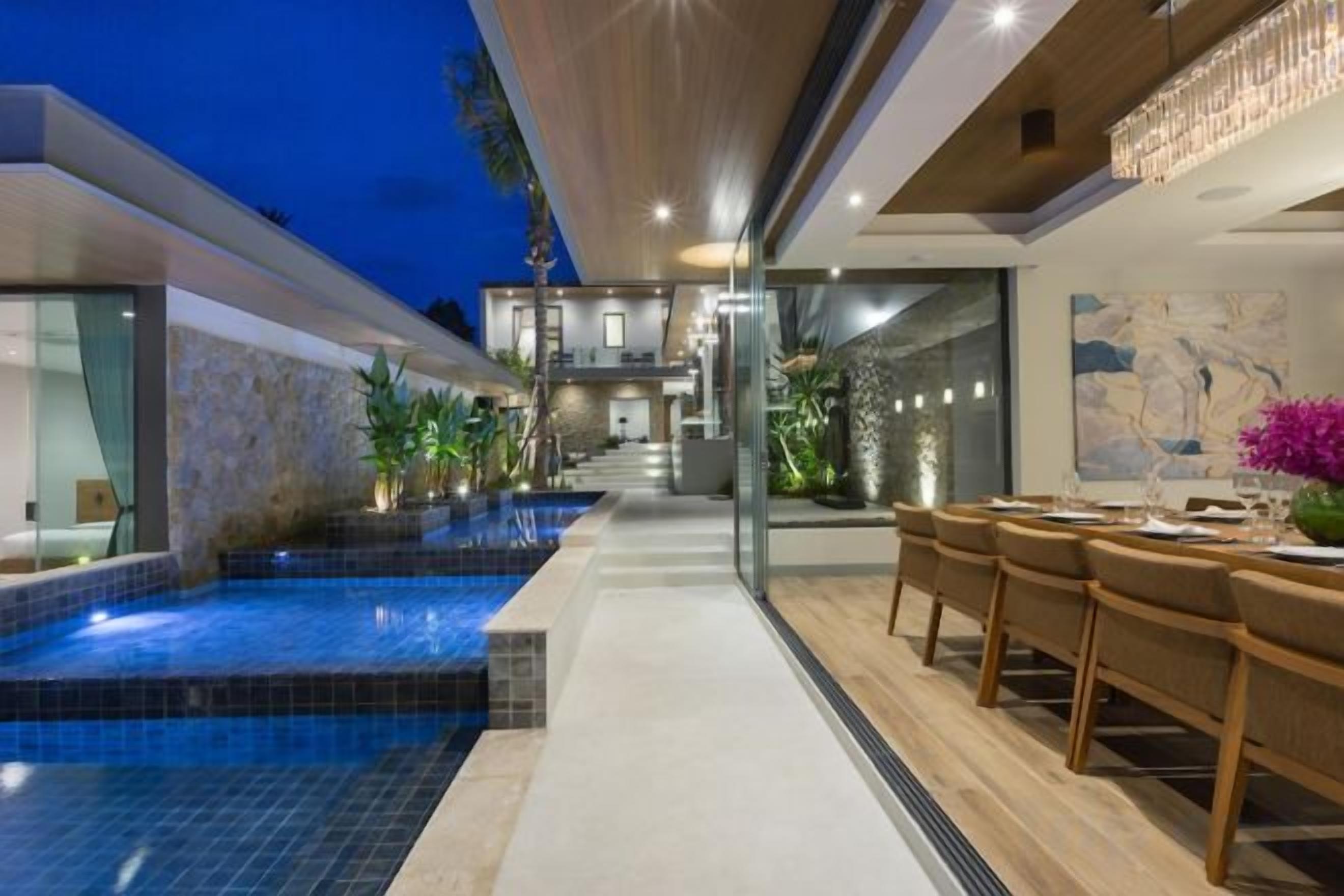 A modern outdoor pool area with a dining setup and a staircase leading to an upper level.