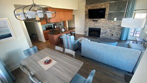A modern open-plan living area with a dining table, sofa, and kitchen in the background. - Regal Vistas 2 BR 2 BA House at Massanutten Resort (Massanutten)