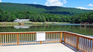 A wooden dock with a sign about fishing regulations, a calm lake, and a forested hill in the background. - Regal Vistas 2 BR 2 BA House at Massanutten Resort (Massanutten)