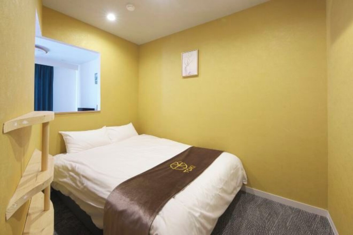 A hotel room with a bed, a mirror, and a small picture on the wall.