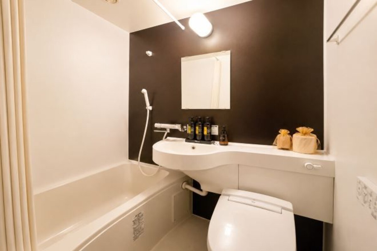 A bathroom with a bathtub, sink, mirror, and toilet.