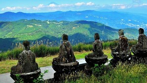 A row of stone statues on a path with a mountainous landscape in the background. - Ito Villa-TOKI- (Ito)