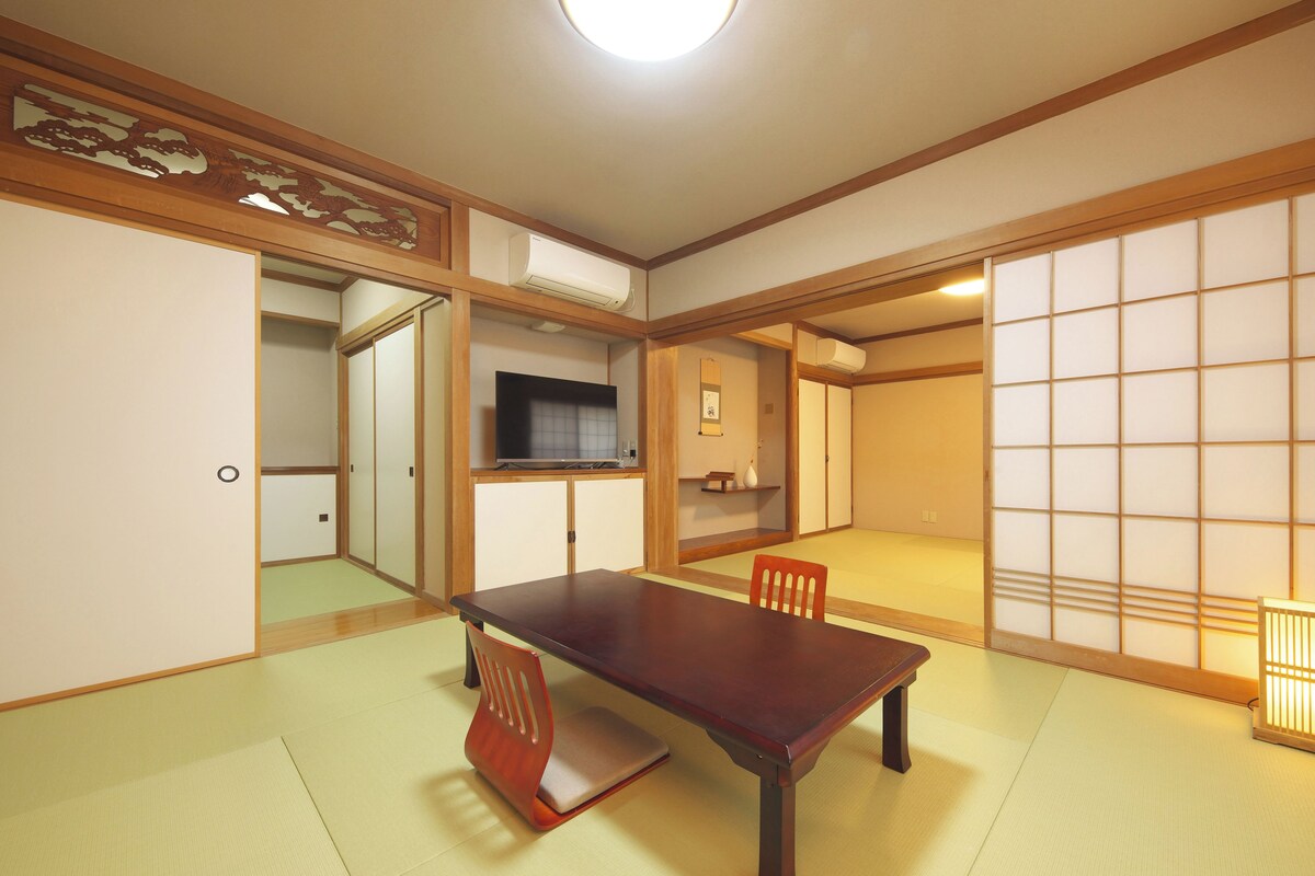 A traditional Japanese-style room with tatami flooring, a low table, and a television.