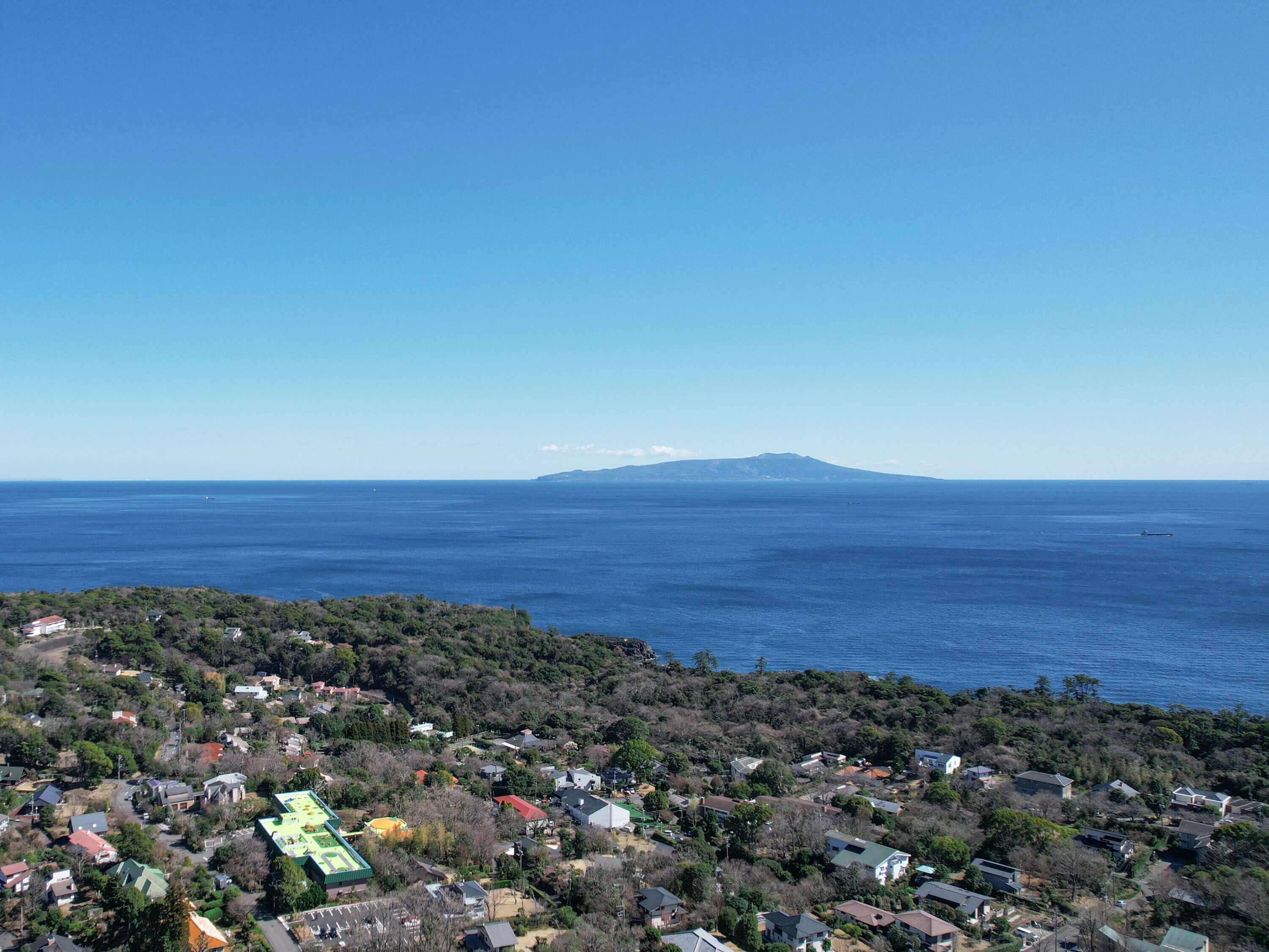 Une zone résidentielle côtière avec des maisons, un bâtiment doté d’un toit végétalisé et une montagne visible au loin.