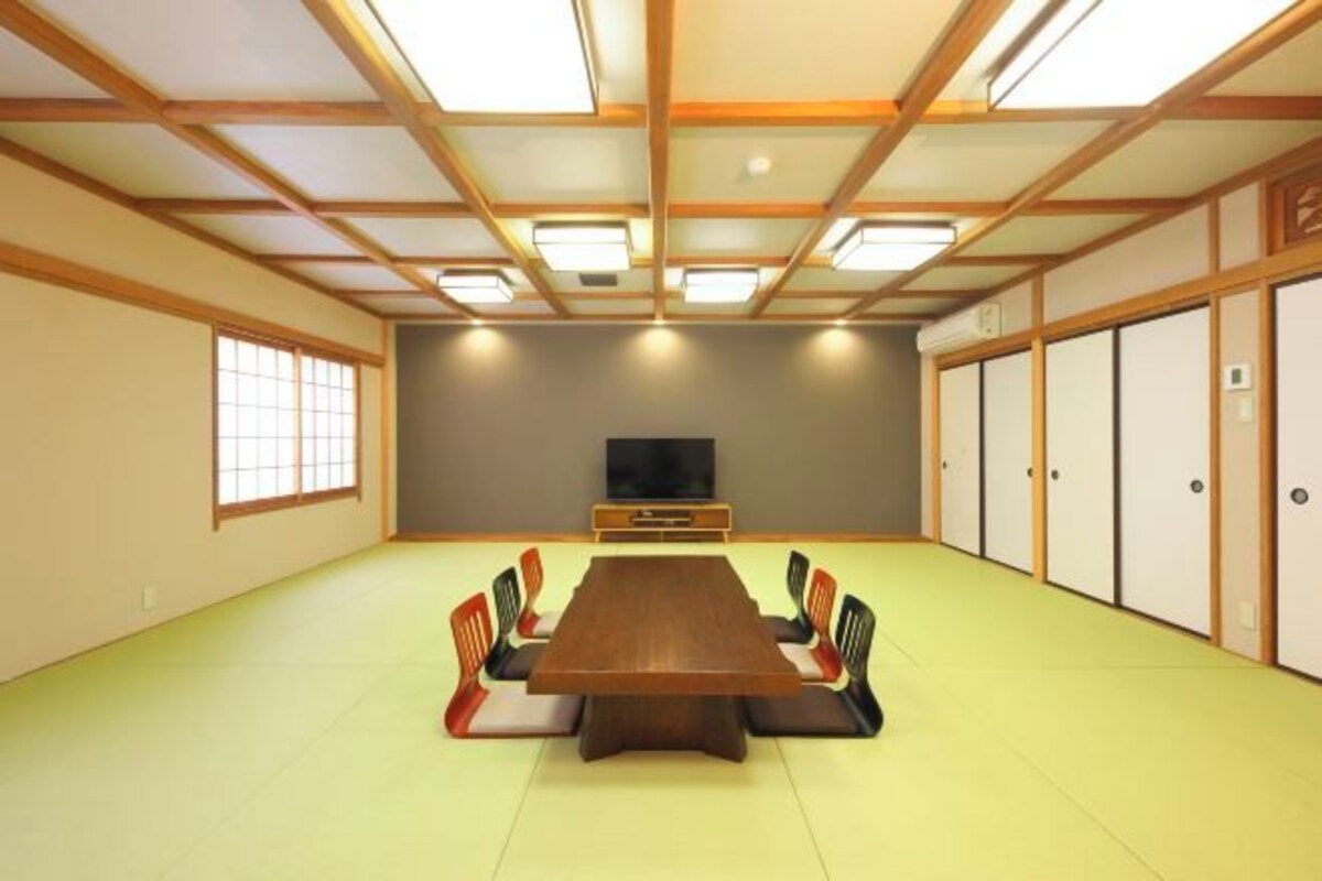 A conference room with a long table, chairs, a television, and sliding doors.