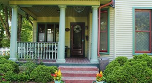 A porch with a white railing, a door with a wreath, and a mailbox. - The Trillium House at DePauw - 4/5 BR 3.5 BA (Greencastle)