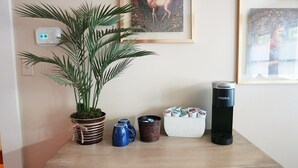A small table with a potted plant, a thermos, a coffee maker, and a mug. - The Trillium House at DePauw - 4/5 BR 3.5 BA (Greencastle)