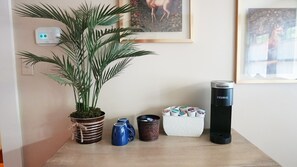 A small table with a potted plant, a thermos, a coffee maker, and a mug.