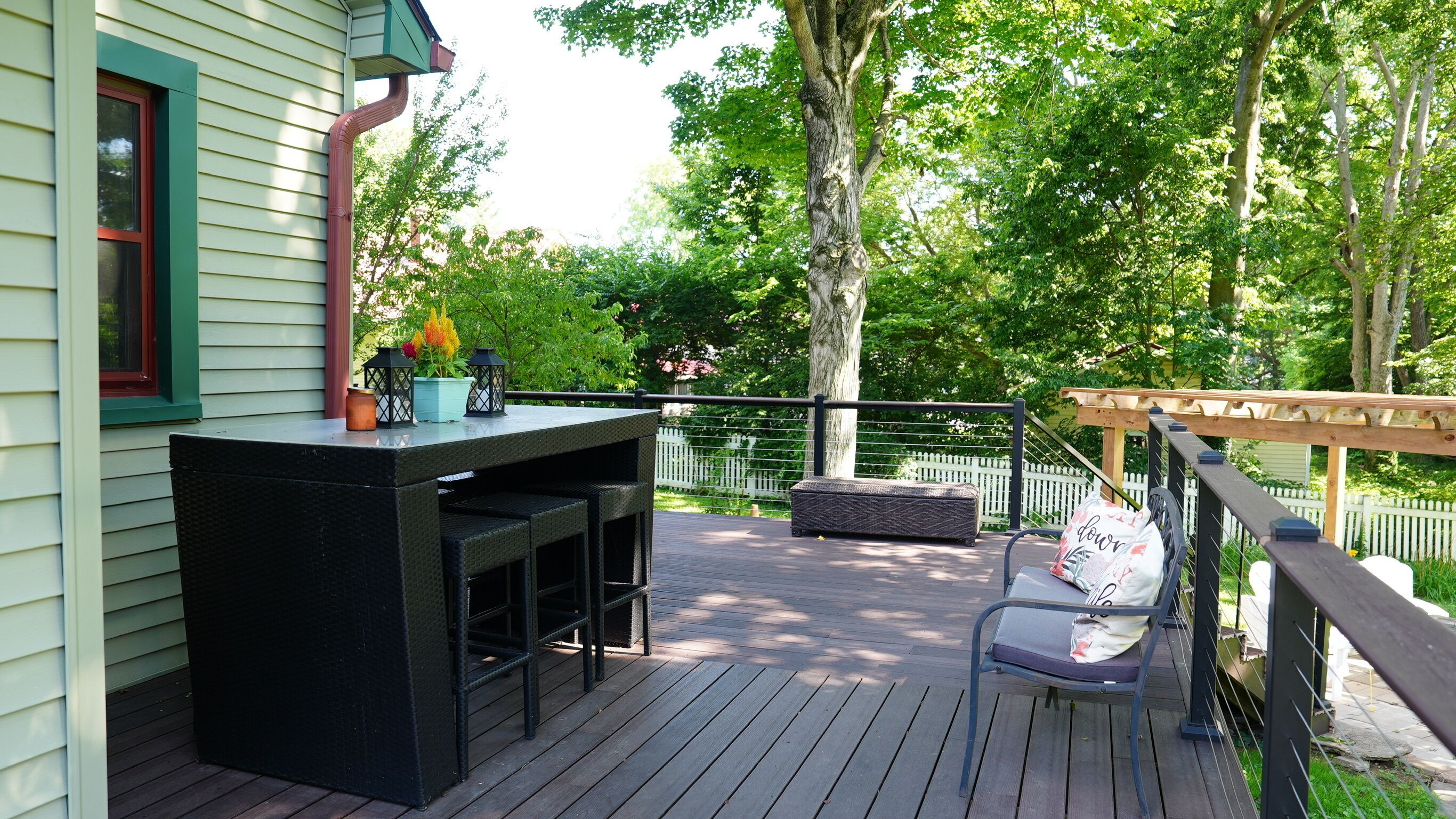 A deck with a bar area, outdoor seating, and a pergola.