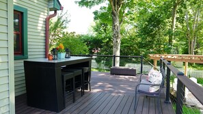 Una terraza con zona de bar, asientos exteriores y una pérgola.