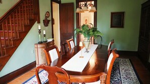 Ein Esszimmer mit Holztisch, Stühlen, einer Chandelier und einer Treppe.