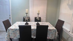 Une table à manger recouverte d’une nappe à motifs floraux, quatre chaises, deux bougies et des décorations en forme d’étoiles de mer.