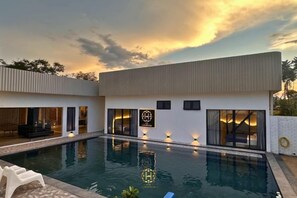 Una casa moderna con piscina, ventanas amplias e interior luminoso.