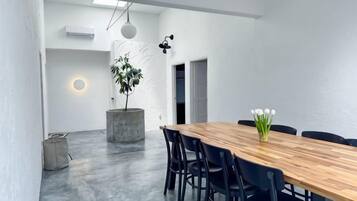 A modern dining area with a wooden table and black chairs, a potted plant, and a wall-mounted light fixture.