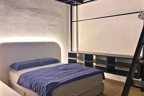 Un dormitorio moderno con cama, cabecera, estantería adosada a la pared y escalera.