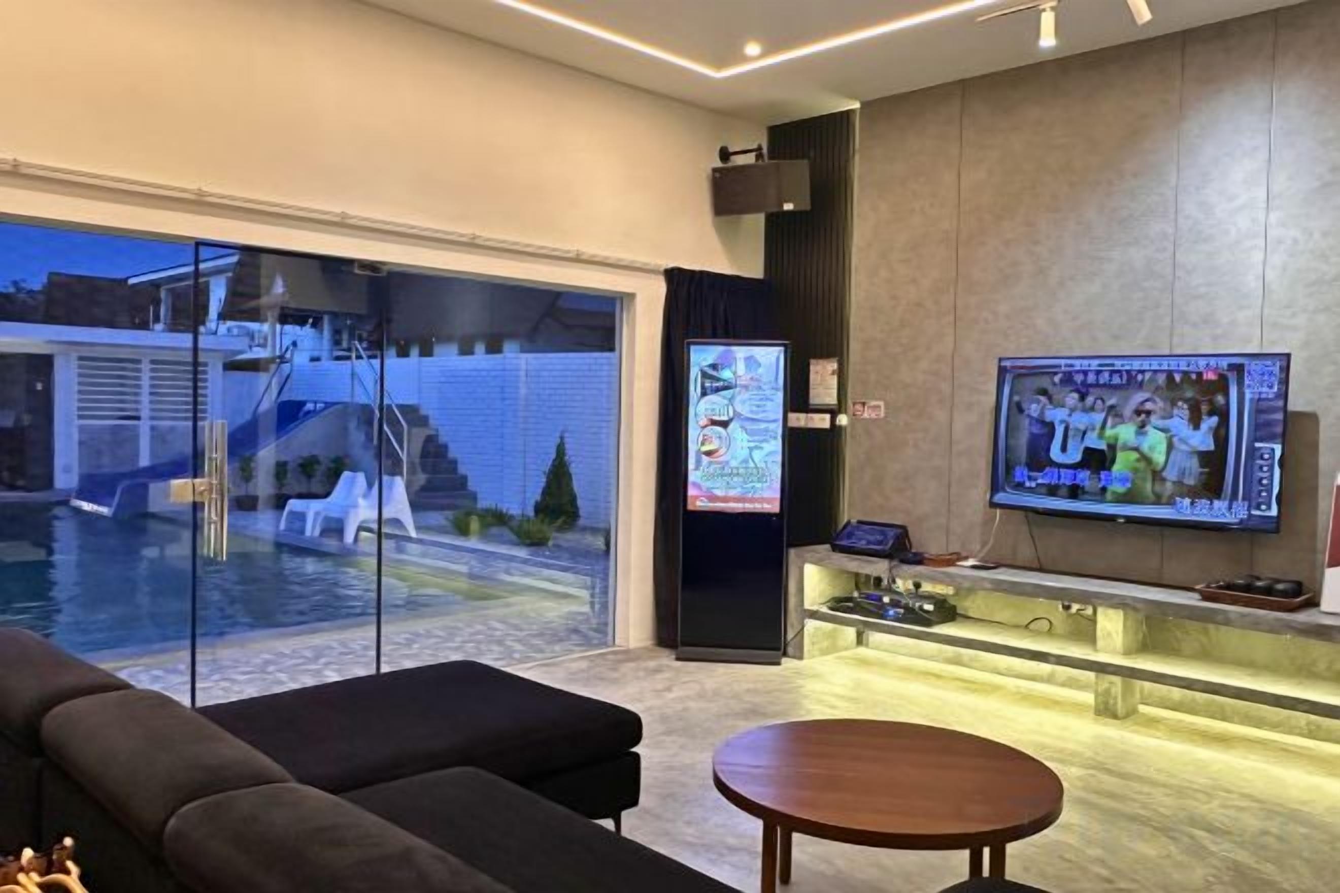 Un salon moderne doté d’un téléviseur, offrant une vue sur la piscine et comprenant un coin bar.