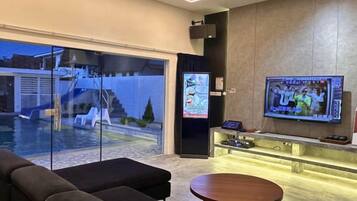 A modern living room with a television, a pool view, and a bar area.