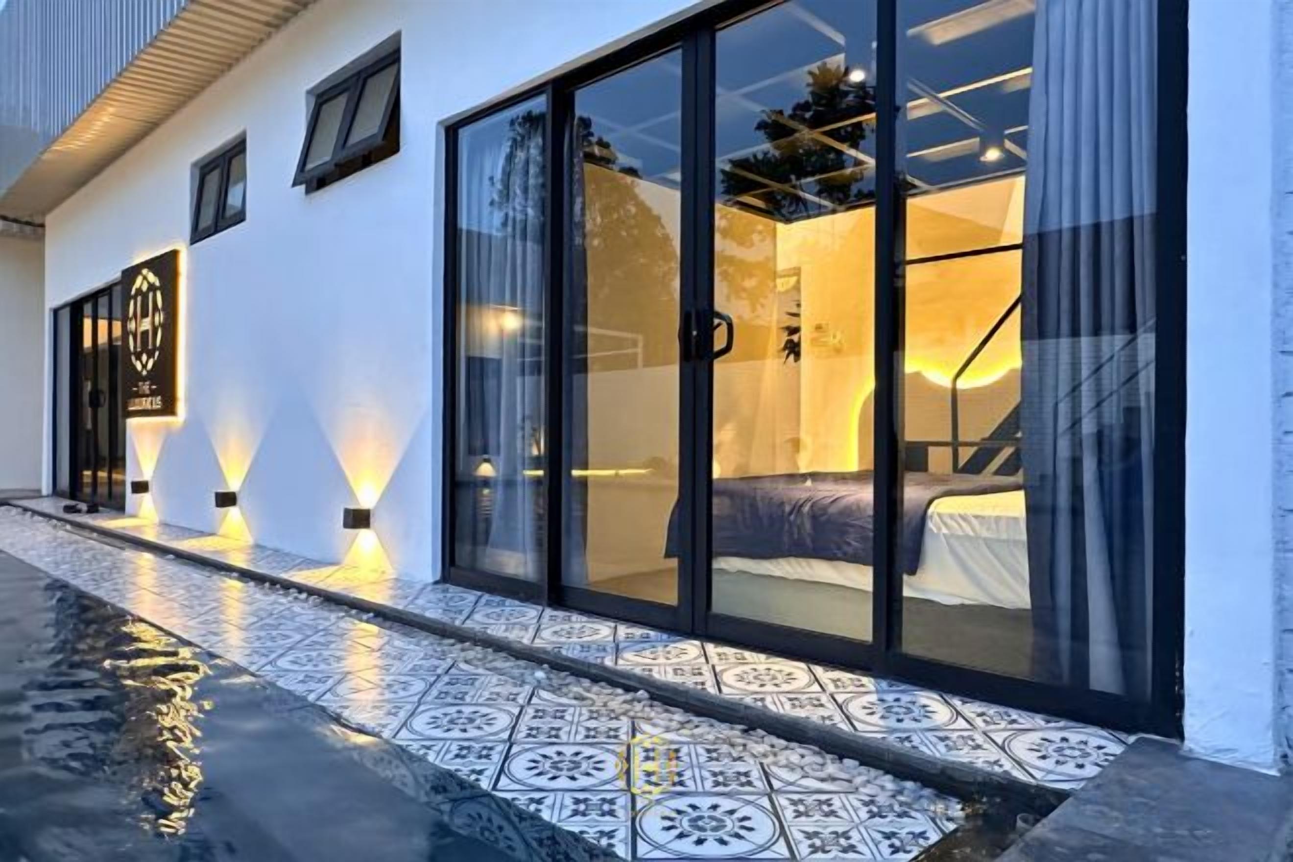 A modern hotel room with a large sliding glass door, a bed, and a visible bathroom.