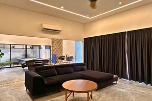 A modern living room with a sectional sofa, a round coffee table, and a desk with a chair. - The Luxurious 1256, Forest Flow Villa (Pegoh)