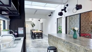 Una cocina moderna con encimera de mármol, una zona de comedor con mesa y sillas, y una pared de ladrillo.
