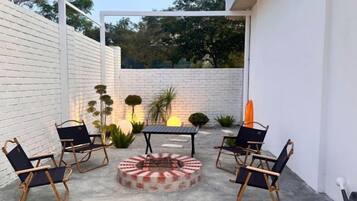 An outdoor patio with a fire pit, seating, and potted plants.