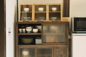 Una cocina con microondas, armarios y estantes con vajilla.