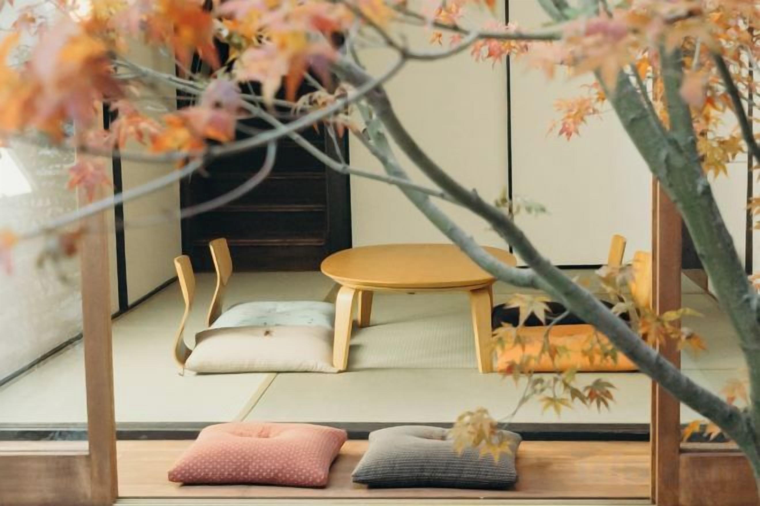 Um quarto japonês tradicional com tatames, uma mesa de madeira baixa e almofadas.