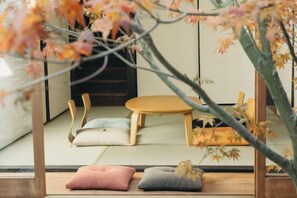A traditional Japanese room with tatami flooring, a low wooden table, and cushions.