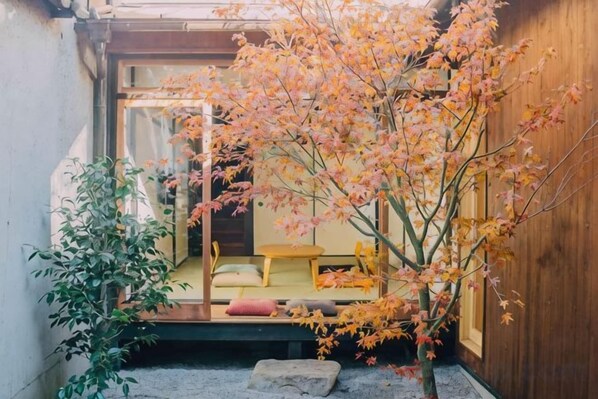 A traditional Japanese-style room with tatami flooring, a low wooden table, and a sliding door leading to a tatami room.