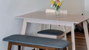 Een eettafel met een bloemetjesvaas, twee stoelen en een bank.