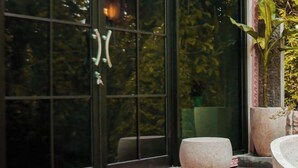 A modern interior with large windows, a stone bench, and potted plants. - Villa Kamar Tamu Selomartani (Kalasan)
