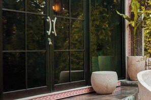 A window with a view of greenery, a stone planter, and a window sill.