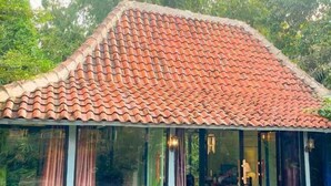 A building with a red-tiled roof and a glass structure with curtains. - Villa Kamar Tamu Selomartani (Kalasan)