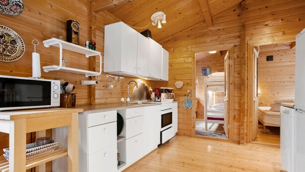 A wooden cabin interior with a kitchen area featuring a microwave, sink, and cabinets. - 3 bedroom stunning home in Spøttrup (Spøttrup)
