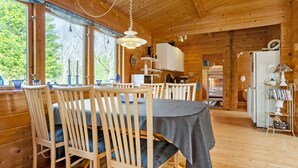 A wooden cabin interior with a dining area, kitchen, and a view of the outdoors. - 3 bedroom stunning home in Spøttrup (Spøttrup)