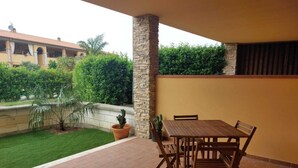 A patio with a wooden table and chairs, surrounded by a stone pillar and a yellow wall. - Located in a quiet and pleasant setting a stone's throw from the sea (Toscana)