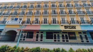 Um edifício de vários andares com varandas, um restaurante chamado "ROTZIU" no andar térreo e uma placa indicando "CILAT AVENUE" no segundo andar.