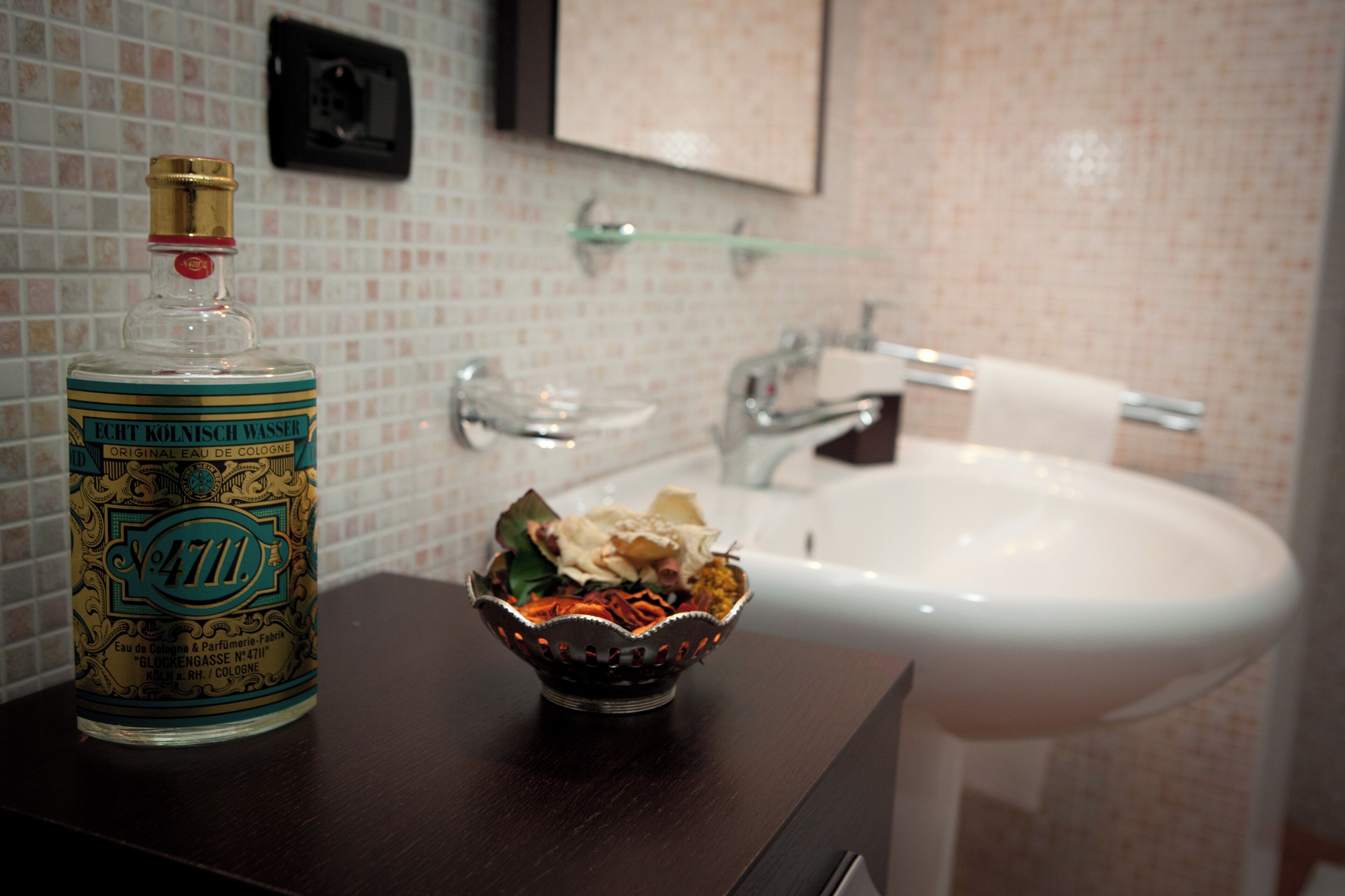 Un baño con un frasco de agua de Colonia, un cuenco decorativo y un lavamanos.