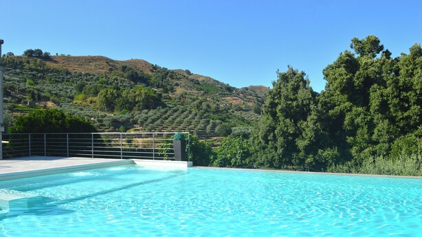 A clear blue swimming pool with a view of a hilly landscape and dense trees in the background. - B&B Mauro Home bed&relax (Linguaglossa)