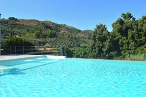 A clear blue swimming pool with a view of a hilly landscape and dense trees in the background. - B&B Mauro Home bed&relax (Linguaglossa)